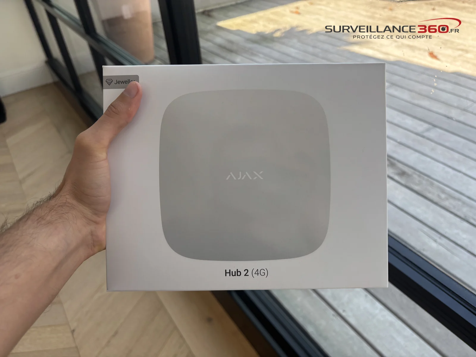 Boîte de la centrale Ajax Hub 2 4G tenue en main avant installation